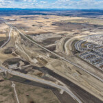 The western extent of the Highway 22X corridor with earthworks in the foreground, as well as new road alignment in the median of Highway 22X and to the north (looking northwest)