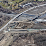 Trucks placing embankment for the approach to the new bridge on Highway 8 crossing the Elbow River (looking southwest)